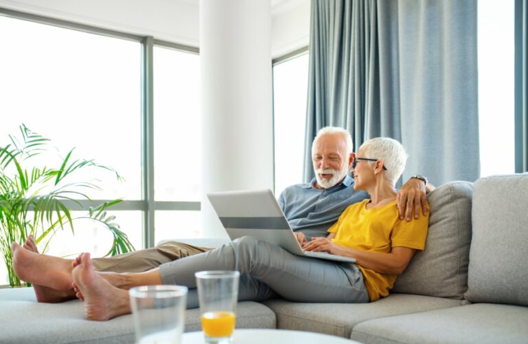 Älteres Paar mit Laptop auf der Couch